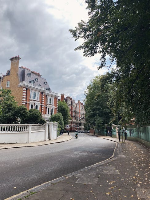 A quiet street in Chelsea SW3, featuring a row of historic red-brick and stucco period properties with ornate facades, decorative chimneys, and mansard roofs. Mature trees line the sidewalk, their lus